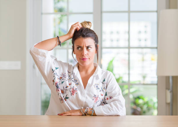 Young woman at home confuse and wonder about question. Uncertain with doubt, thinking with hand on head. Pensive concept.