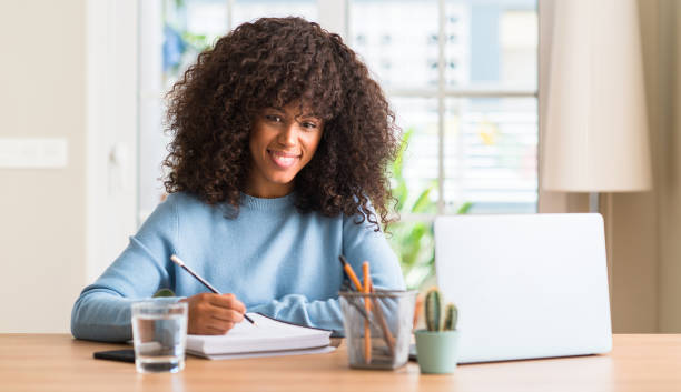 istock African american woman studying at home using a computer laptop with a happy face standing and smiling with a confident smile showing teeth 1041314564