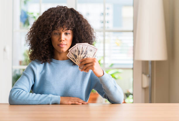 istock African american woman holding dollar bank notes with a confident expression on smart face thinking serious 1041314906