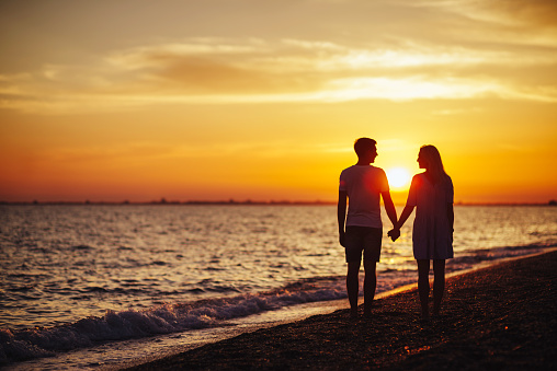 Young happy couple on seashore in the lights of sunset.