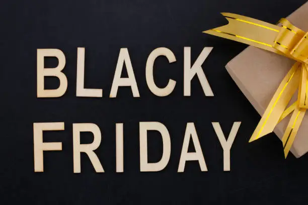 Photo of black Friday - text in wooden letters on blackBoard  with gift . Copy space