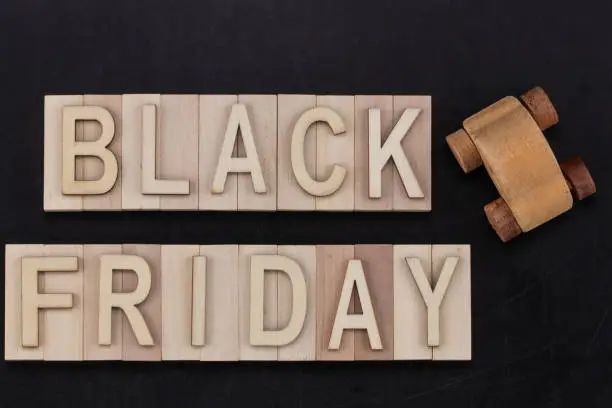 Photo of black Friday - text in wooden letters on blackBoard  with wooden car. Copy space