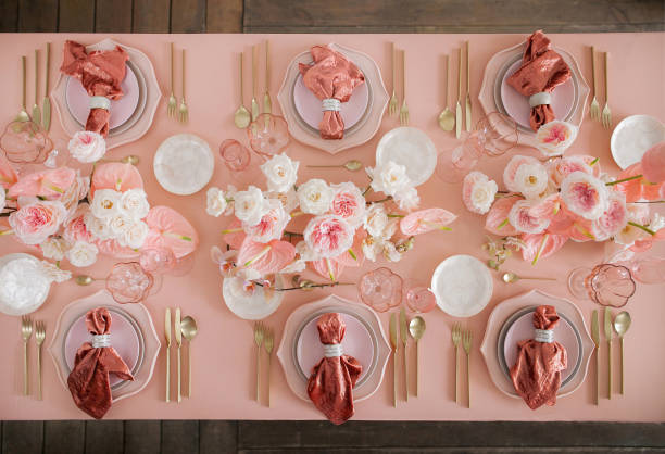 Festive table decor. In pastel pink colors with golden cutlery. With different natural colors roses, peonies, anthurium. Luxury wedding, party, birthday. View from above Festive table decor. In pastel pink colors with golden cutlery. With different natural colors roses, peonies, anthurium. Luxury wedding, party, birthday. View from above golden roses stock pictures, royalty-free photos & images