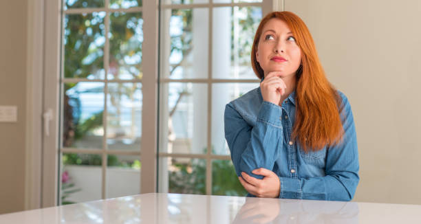 istock Redhead woman at home serious face thinking about question, very confused idea 1041348506