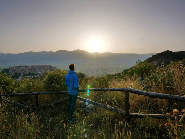 istock Young man watching sunrise over Teggiano 1041359034
