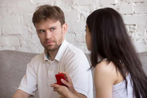 Decisive girlfriend making marriage proposal to frustrated boyfriend, presenting engagement ring, feminist woman asking surprised puzzled lover to marry, setting family. Feminism concept