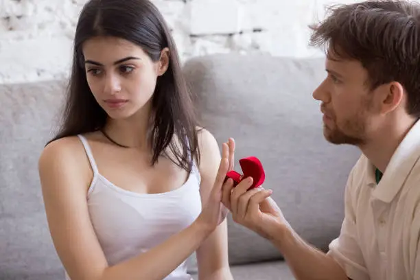 Photo of Dissatisfied woman rejecting marriage ring from boyfriend