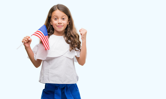 Brunette hispanic girl holding flag of United States of America screaming proud and celebrating victory and success very excited, cheering emotion