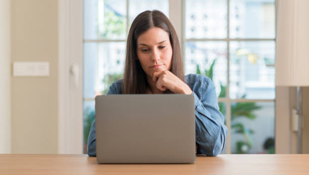 istock Young woman using laptop at home serious face thinking about question, very confused idea 1041369048