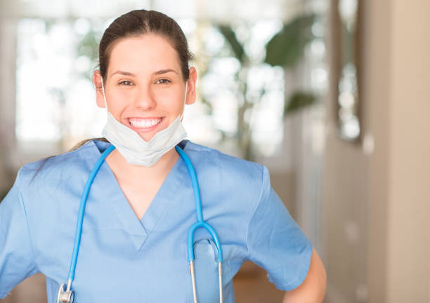 junge krankenschwester frau mit maske und stethoskop mit ein glückliches gesicht stehen und lächeln mit einem zuversichtlich lächeln zeigt zähne - toothy smile relaxation white healthcare and medicine stock-fotos und bilder