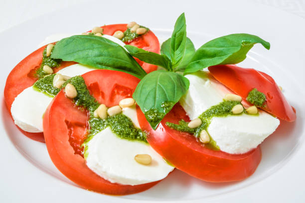 istock Delicious sliced tomatoes and cheese with herbs, on a white plate. Horizontal frame 1041394490