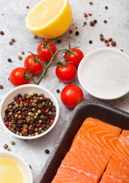 istock Plastic container with fresh salmon slice with oil tomatoes and lemon on stone kitchen background. With rosemary and salt 1041406484