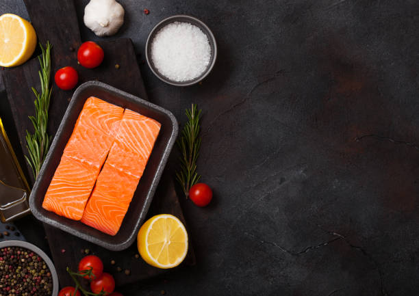 istock Plastic container with fresh salmon slice with oil tomatoes and lemon on stone kitchen background. Space for text 1041410136