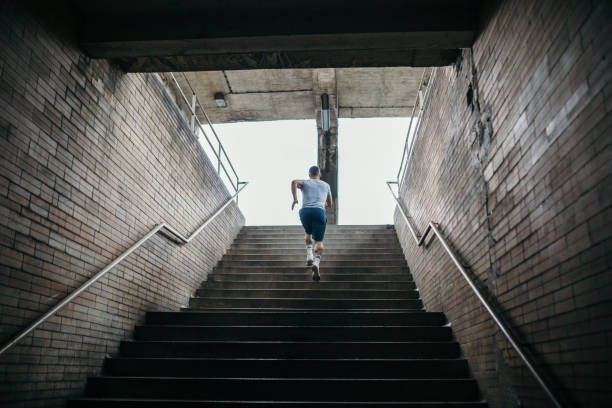 young male athlete running up the stairs - adult jogging running motivation imagens e fotografias de stock