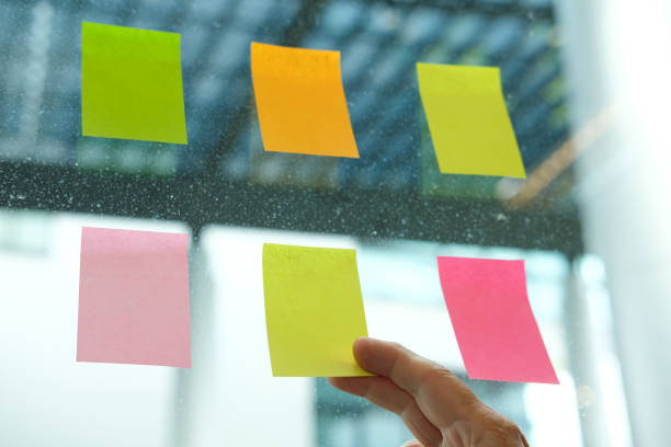 istock hand hold adhesive notes on glass wall. Sticky note paper reminder schedule for creative idea & business brainstorming 1041460302