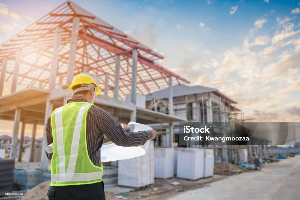 Professional engineer architect worker with protective helmet and blueprints paper at house building construction site Professional engineer architect worker with protective helmet and blueprints paper at house building construction site background Construction Industry Stock Photo