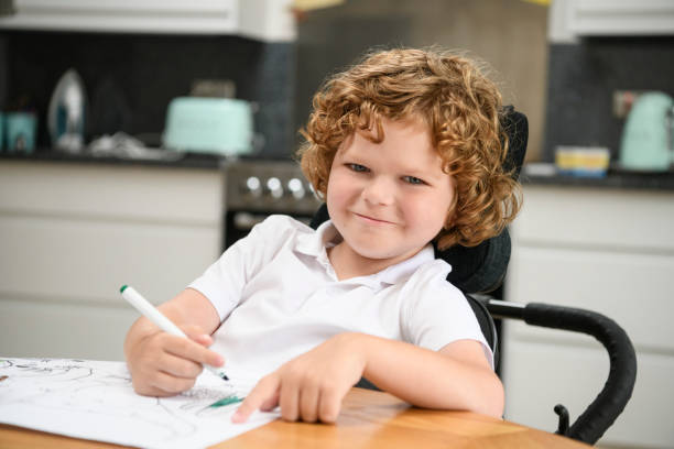 giovane ragazzo disabile che disegna a casa - physical impairment smiling front view looking at camera foto e immagini stock