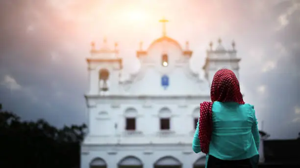 Photo of Christian Woman praying to God near church