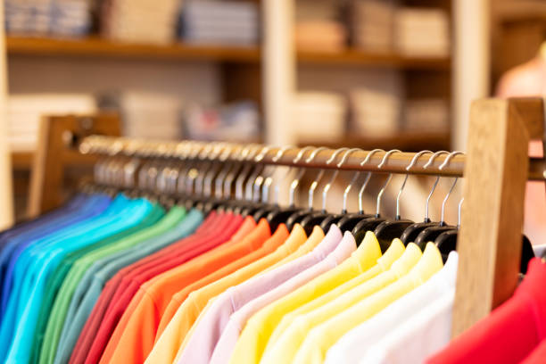 fila de color camisetas en una tienda - shirt hanger hanging blue fotografías e imágenes de stock
