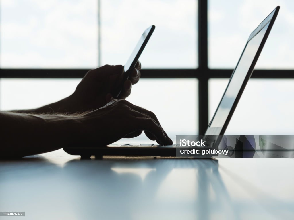 online payment authorization mobile phone password secure online payments. two factor authorization. man hands holding mobile phone and entering password message on laptop. Digital Authentication Stock Photo