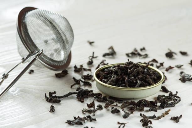 chinese red, black tea and brew sieve on white wooden table - garble imagens e fotografias de stock