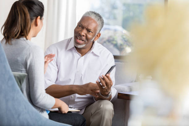 istock Serious senior man holds smartphone while talking with therapist 1041483714