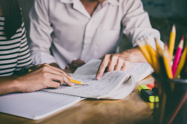istock High school or college student group catching up workbook and learning tutoring in classroom and reading, doing homework and lesson practice preparing exam 1041485348