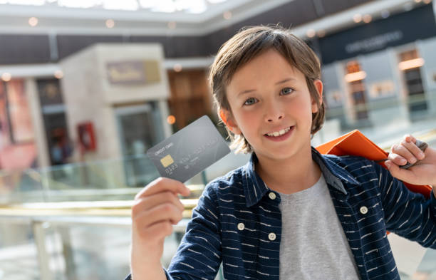 ショッピング モールでショッピング、クレジット カードを保持している幸せ��な少年 - paying children only retail childhood ストックフォトと画像