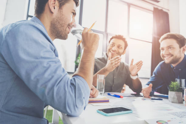 agua potable de jóvenes empresarios de sonriendo y discutiendo el nuevo proyecto, concepto de negocio trabajo en equipo - office water business meeting fotografías e imágenes de stock