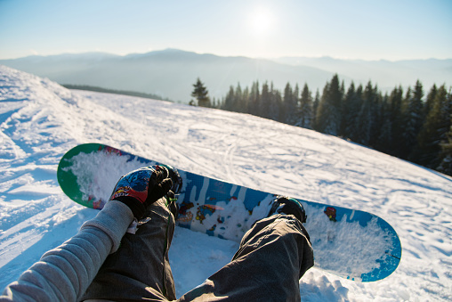 Point of view shot of a female snowboarder lying on the snow on the slope relaxing after riding