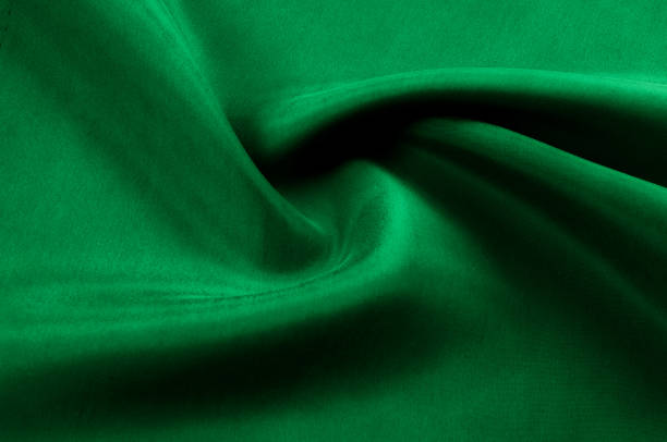istock Background texture, pattern. Thick thick silk fabric is green. This satin fabric is ideal for creating a smooth flow in design, it has a liquid drape and exquisite shine. 1041508790