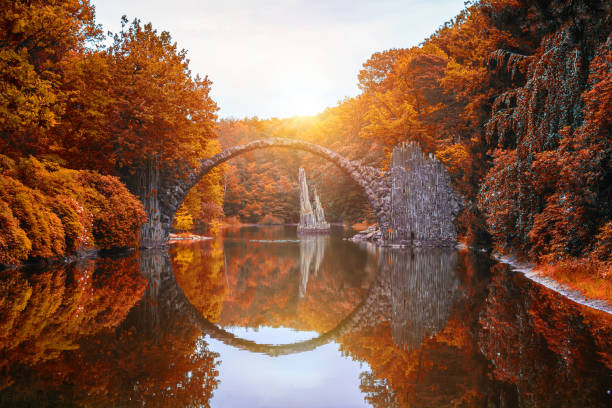 puente rakotz (rakotzbrucke, puente del diablo) en kromlau, sajonia, alemania. otoño colorido, reflejo del puente en el agua crean un círculo completo - natural column fotografías e imágenes de stock