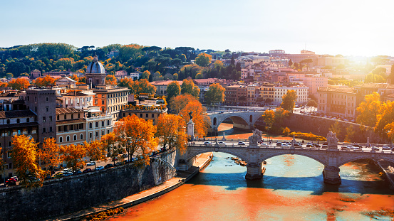 Skyline with bridge Ponte Vittorio Emanuele II and classic architecture in Rome, Vatican City scenery over Tiber river. Autumn view with red foliage.