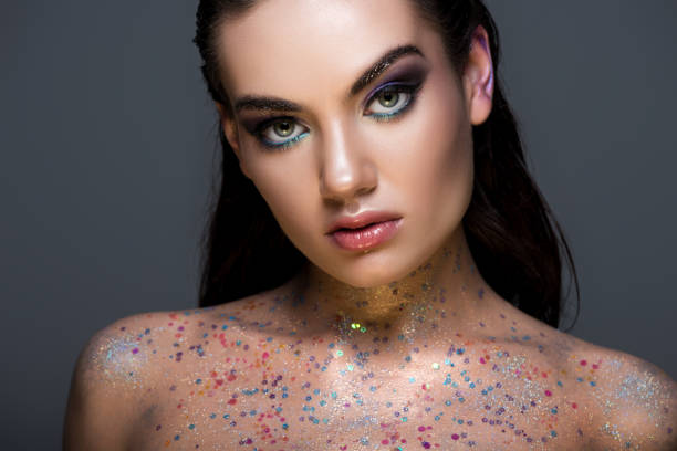 istock beautiful glamorous young model posing with glitter on body and looking at camera, isolated on grey 1041514748