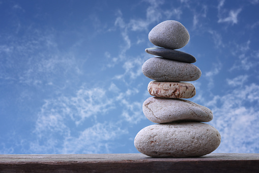 Balance Stones stacked to pyramid in the blue sky background to Spa ideas design or freedom and stability concept on rocks.