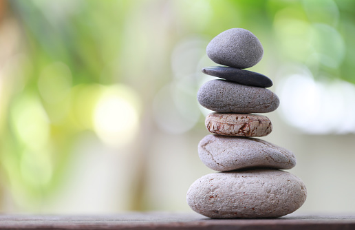 Balance Stones stacked to pyramid in the soft green background to Spa ideas design or freedom and stability concept on rocks.