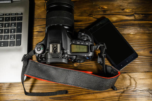 istock Modern DSLR camera, smartphone and laptop on wooden table. Top view 1041553622