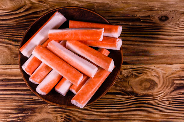 istock Ceramic plate with crab sticks on wooden table. Top view 1041553650
