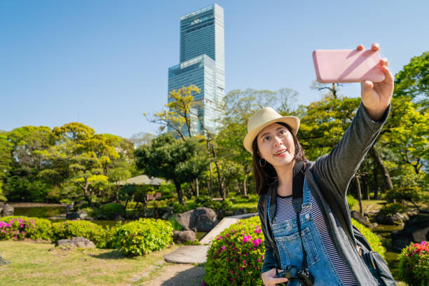 istock woman taking selfie with skyscraper in garden. 1041579982