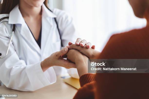 Asian Doctor Woman Encourage Young Woman Patient By Holding Hand Stock Photo - Download Image Now