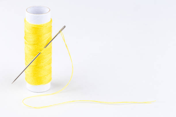istock Spool of yellow threads and a needle on white background 1041634024