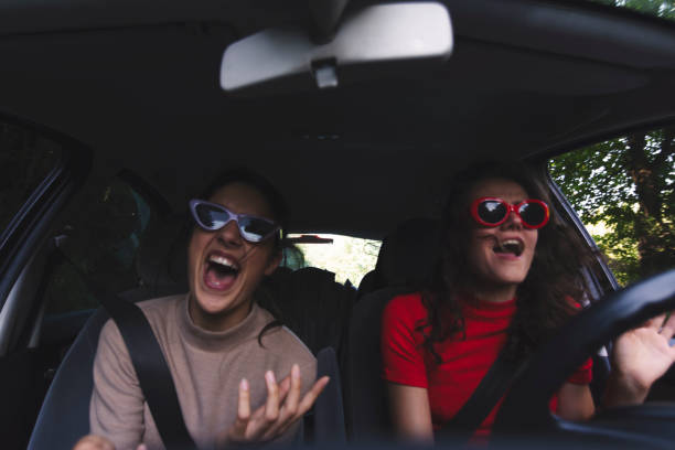 Two happy young women having fun in car Two young women traveling in car singing stock pictures, royalty-free photos & images