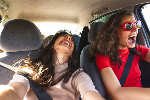 Two happy young women having fun in car
