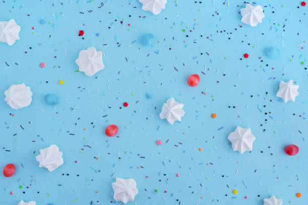 istock White meringues and colorful confetti on blue background, pattern. 1041637490