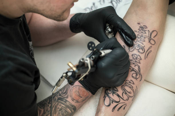 Tatooing Tattoo artist tattooing an unrecognizable Caucasian male model. . forearm tattoos men stock pictures, royalty-free photos & images