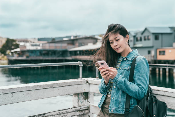 istock woman checking her phone while visiting port 1041658056