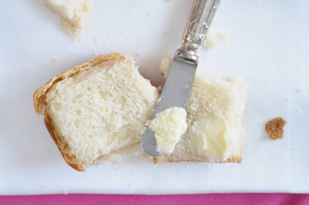 spreading butter on bread, top view stock photo
