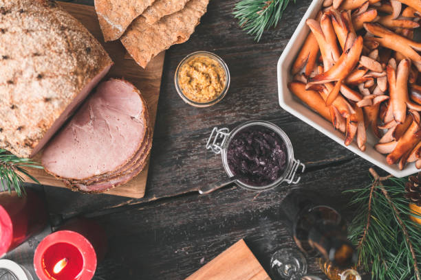 A traditional Swedish Christmas buffet dinner on a dark wooden table, decorated with pine needles, pine cones and candles.