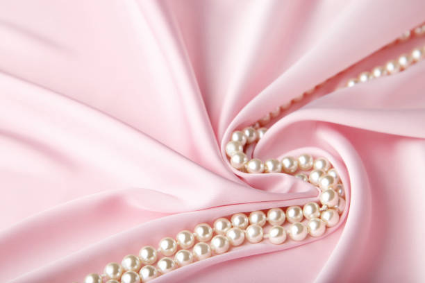 istock Pearl necklace on pink satin fabric 1041708236