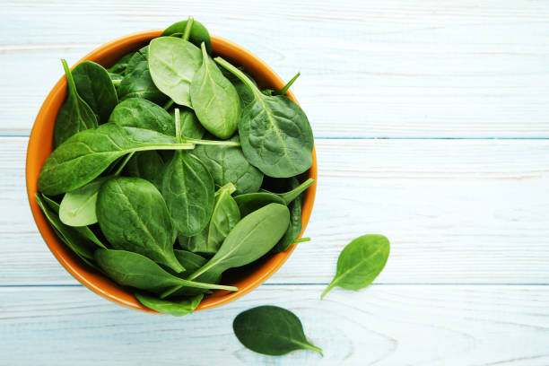 istock Spinach leafs in bowl on wooden table 1041709512